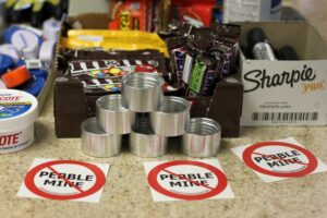 Photo of "no Pebble mine" stickers next to store counter goodies like candy, sharpies, small tins