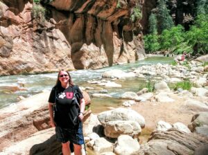 Catherine hiking the Zion Narrows with river and canyon walls in background