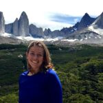 Hannah standing before forest and rocky peaks.